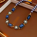 Vintage necklace with blue gemstones and grey pearls on a luxury jewelry box - Necklace-Blue