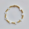 Detalle macro de las cuentas chapadas en oro de 18K y dijes de corazón de concha natural - Dorado Blanco Concha