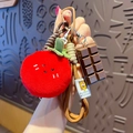 Red plush tomato pendant with chocolate charm on a brown braided strap keychain - Plush Food-Tomato + Chocolate