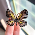 Elegante vergulde vlinderbroche met kleurrijke strassteentjes tussen de vingers - Geel Oranje Zwart Vlinder