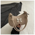 Detalle de bolso hobo beige con lazo de metal plateado y elegante asa de hombro anudada - Caqui