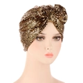 Detailed close-up of golden sequin turban hat with a large bow on white background - Gold