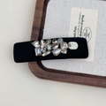 Dettaglio di un fermaglio per capelli nero con strass scintillanti su vassoio di legno - Fermaglio BB Largo