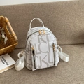 Dettaglio zaino in pelle bianca con stampa LUCK su sfondo di tessuto beige morbido - Bianco