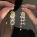 Gros plan de boucles d'oreilles pendantes dorées avec strass et perles de cristal - Gland en Goutte Creuse Sphérique (10#)
