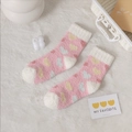 Rosa Korallenvlies-Socken mit bunten Herzmustern auf einer weichen Plüschdecke - Rosa Herz