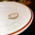 Détail d'une bague dorée avec perles blanches et zircons dans un plat en céramique - Or (Plaqué Or Véritable)