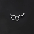 Spilla in metallo argento con struttura molecolare chimica su sfondo nero - Molecola di Serotonina