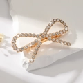 Close-up of golden bow hair clip with sparkling rhinestones and elegant pearls - Rhinestone Gold