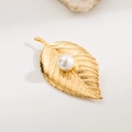 Golden leaf brooch with central white pearl and detailed veins on stone background - Gold Leaf