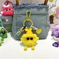 Détail du porte-clés monstre en peluche jaune avec lunettes sur un sac en jean - Jaune
