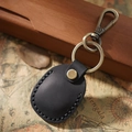 Retro black leather AirTag case with metal keychain set on a vintage map background - Black