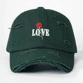 Detail van roos borduurwerk en LOVE tekst op versleten donkergroene baseballpet - Eén maat / Donkergroen