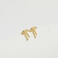Detailed view of gold ribbon bow stud earrings on a minimalist white geometric stand - M / Gold - Medium