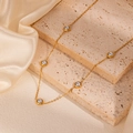 Detail of a gold necklace with grey pearls on marble base and soft silk backdrop - Gold Round White Pearl