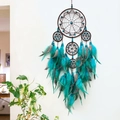 Handmade dreamcatcher with turquoise beads and grey spotted feathers hanging on a white wall - Blue