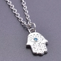 Vista macro del ciondolo Mano di Fatima argento con occhio blu su base scura - Set Collana Argento