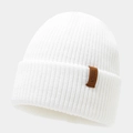 Close-up of white ribbed knit beanie with brown leather patch and detailed stitching - White