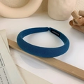 Detail showing blue padded wide headband with a black handmade woven label on white surface - Dark Blue