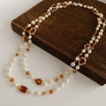 Détail d'un collier de perles vintage avec gemmes ambrées et chaîne dorée élégante - Marron