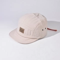Detailed macro view of beige nylon 5-panel hat with leather logo patch and metal eyelets - Adjustable / Beige