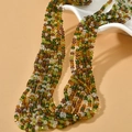 Close-up of 3mm mixed color beaded necklace featuring green and brown beads on white porcelain - Brown Green