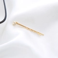 Close-up of golden moon-shaped hair clip with three inlaid rhinestones on white fabric - Small Moon