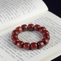 Polished blood sandalwood barrel bead bracelet placed on a classic book - Blood Sandalwood Classical Beads / 12mm*17 Beads / Reddish Brown