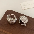 Detail van zilveren geribbelde oorbellen met parelaccenten op donkere houten achtergrond - Schelpvorm / Zilver