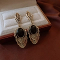 Dettaglio macro di orecchini vintage a foglia d'oro con pietra nera su portagioie - 36# Perno Argento Oro Nero