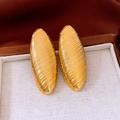 Close-up of golden oval earrings with diagonal textured surface in a wooden box - Gold