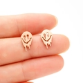 Macro shot of melting gold smiley face earrings on fingertips for size detail - Rose Gold