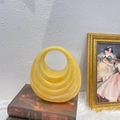 Artistic detail of a yellow circular ring glass vase with concentric textures on vintage books - Champagne