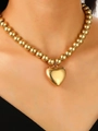 Collier à billes dorées avec grand pendentif cœur évidé porté par un mannequin femme - Chaîne de billes dorée avec grand pendentif coeur