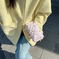 Dettaglio di una trousse rosa trapuntata tenuta in mano con luce naturale all'aperto - Orso Ciambella