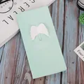 Biglietto d'auguri verde chiaro con ala 3D, graffetta e busta su tavolo in legno - Ali 3D / Verde