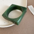 Detail view of square marble resin bangle in dark green with white swirls on ceramic plate - Dark Green Marble Pattern