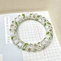 Spiral clover leaf hair tie with green pattern and golden petal accents on base - Gardenia