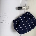 Flat lay of navy blue polka dot chiffon makeup bag with skincare bottle and magazine - Blue Polka Dot Shrapnel Bag