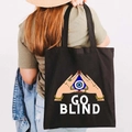 Graffiti Greek Evil Eye black canvas tote bag worn by a model in a lifestyle setting - Design L-GO BLIND-Black