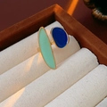 Détail d'une bague dorée ovale avec émail bleu et vert sur un présentoir en velours - Vert - Bleu