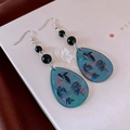 Close-up of retro wheat tassel earrings with blue gradient teardrops on a vintage book - Retro Blue-Green Gradient Teardrop (Ear Hook)