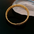 Macro-opname van de goudkleurige dubbellaagse kralenarmband met glanzende metaaltextuur - Goud