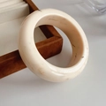 Nahaufnahme eines breiten elfenbeinfarbenen Harzarmreifs mit brauner Maserung im Detail - Rund / Creme