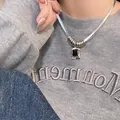 Detail van een zilveren dubbele ketting met zwarte edelsteen op een casual model - Platte Slangenketting Zwarte Edelsteen