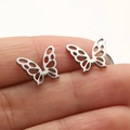 Brushed silver stainless steel butterfly wing stud earrings shown on fingertip - 671 Matte Hollow Butterfly / Steel
