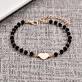 Bracciale di perle minimalista con ciondolo a cuore in oro rosa su sfondo in tessuto - Cuore