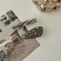 Detail of amber marble resin and gold foil black droplet hair clips on a desk - Gray