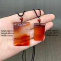 Red agate jade pendant necklaces in large and small sizes held by hand on wood background - Small Plaque (Cord Style)