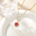 Elegant gold heart necklace with red gemstone and white zircons on white ceramic plate - Red Pendant Necklace